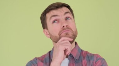 A man who thinks and surveys the environment. He stands on the background in the studio. The guy is concentrated and engrossed in his thoughts, giving a feeling of deep thoughtfulness.