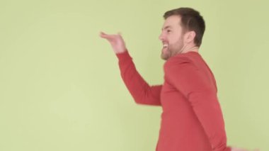 A young man in the background in the studio, he dances with great joy, his movements are very energetic and lively. Sincere emotions in dances