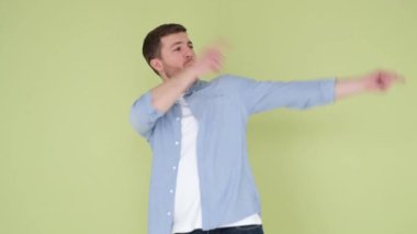 Stüdyo arka planındaki yakışıklı genç adam, büyük bir neşeyle dans ediyor, hareketleri çok enerjik ve canlı.