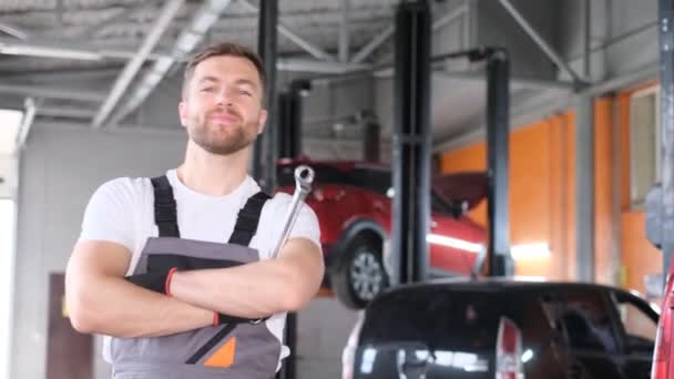 Portret Szczęśliwego Mechanika Kluczem Ręku Stoi Przed Samochodami Warsztacie Samochodowym — Wideo stockowe