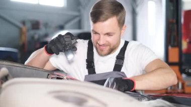 A car mechanic examines a car at a car service, performing a number of tests and checks. Maintenance of cars