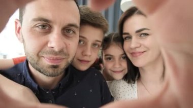 Dad smiling makes a gesture of the heart that reflects his love and conveys warmth and pleasure. Happy young family with sincere love, positive emotions about children and family.