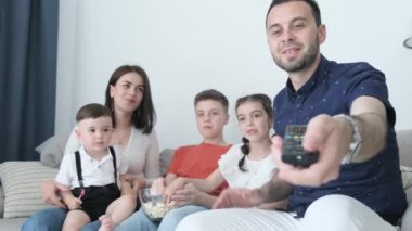 Mutlu aile evde birlikte vakit geçiriyor. Film izliyorlar, sarılıyorlar ve patlamış mısır yiyorlar. Aile üyeleri birlikte geçirdikleri zamandan memnun görünüyorlar.