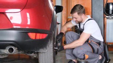 A car mechanic repairs the chassis of a car in a car service. The mechanic checks the chassis for any damage or wear.
