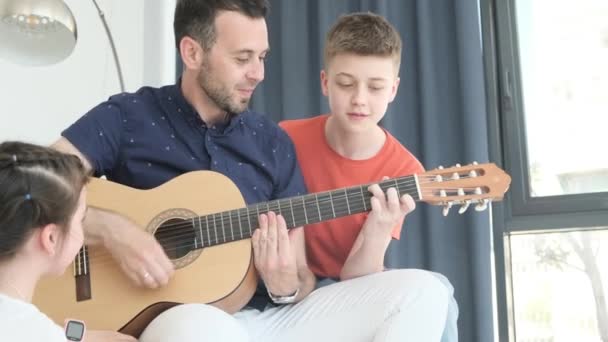 Family Relaxing Home Sitting Sofa Dad Playing Guitar His Kids — Stock Video