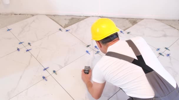 建筑商把瓷砖铺在地板上 穿着制服和头盔的专业工匠 铺漂亮的白色瓷砖 — 图库视频影像