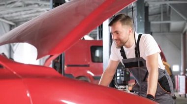 A car mechanic examines a car at a car service, performing a number of tests and checks. Maintenance of cars