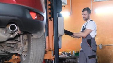 A car mechanic examines a car at a car service, performing a number of tests and checks. Maintenance of cars