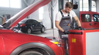A car mechanic examines a car at a car service, performing a number of tests and checks. Maintenance of cars