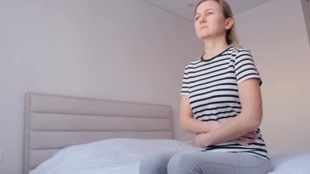 Μια Άρρωστη Γυναίκα Κάθεται Στο Κρεβάτι Και Κρατάει Στομάχι Της — Αρχείο Βίντεο