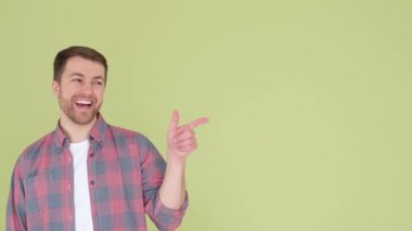 Gömlekli yakışıklı bir adam poz veriyor, işaret parmağını yana çeviriyor. 4k video