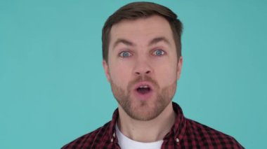 Portrait of a man standing on a blue he looks fascinated by what he sees and his face reflects the impression