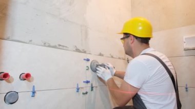 Özel üniformalı bir tamirci ve kask banyodaki seramik fayansları tamir ediyor. Döşeme döşemesi. Modern onarım.