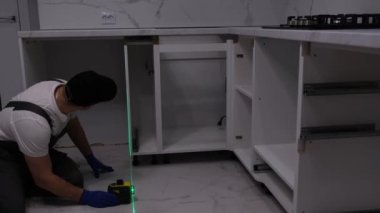A professional master checks the quality of installed furniture in the kitchen. Laser level when assembling furniture.