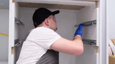 The craftsman installs fittings for kitchen drawers. Modern high-quality kitchen accessories