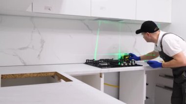 A professional electrician during the installation of a kitchen stove using an electronic level. High-quality arrangement of a new apartment