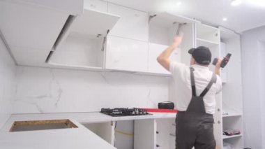 A very funny and cheerful master dances with tools during the repair. The kitchen furniture installer is having fun