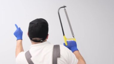 Satisfied happy worker dancing with saw against white wall background. Playful master man