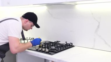 A professional craftsman installs a gas stove in a beautiful white kitchen. Installation of a modern kitchen.
