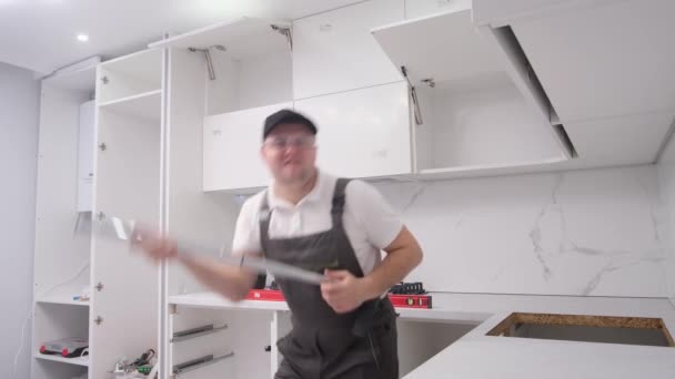 Ein Verrückter Arbeiter Imitiert Das Gitarrespielen Während Eine Küche Einrichtet — Stockvideo