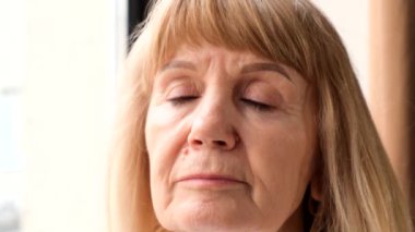 Gözlerini açıp kameraya bakan güzel, modern bir büyükannenin portresi. Yavaş çekim