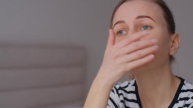 Çekici genç bir kadın evindeki kanepede oturuyor, baş ağrısı çekiyor, yorgun ve endişeli ve depresyondan muzdarip..