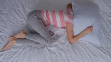 Yalnız ve bunalımlı hamile bir kadın yatağa kıvrılmış bir şekilde yatıyor. Yüksek kalite 4k video