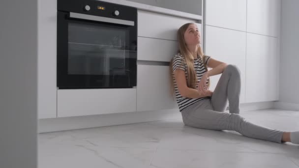 Ung Kvinna Deprimerad Hon Sitter Golvet Köket Hon Har Menstruationscykel — Stockvideo