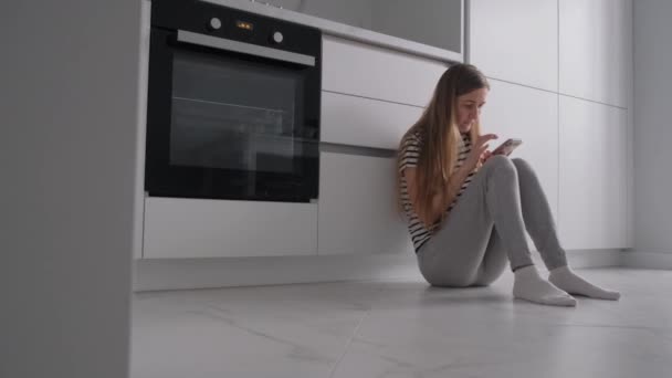 ソーシャルメディアのフィードをスクロールしている女性が 彼女は台所に座って うつ病に苦しんでいます 4Kビデオ — ストック動画