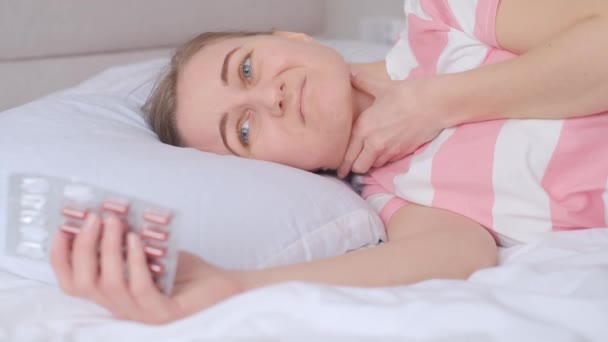 喉が痛い若い女性がベッドの上に寝そべっている インフルエンザの最初の症状 4Kビデオ — ストック動画