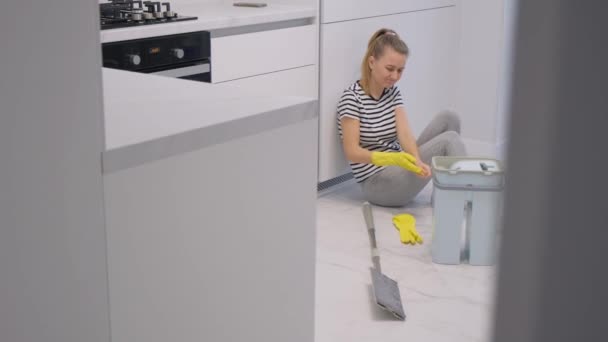 アパートを掃除するのに疲れた女が床に腰を下ろして休んでいる 掃除だ 4Kビデオ — ストック動画