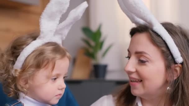 妈妈和女儿在厨房里画复活节彩蛋 一个快乐的家庭正在为复活节作准备 复活节的时候 可爱的小女孩在兔子的耳朵里 复活节快乐 — 图库视频影像