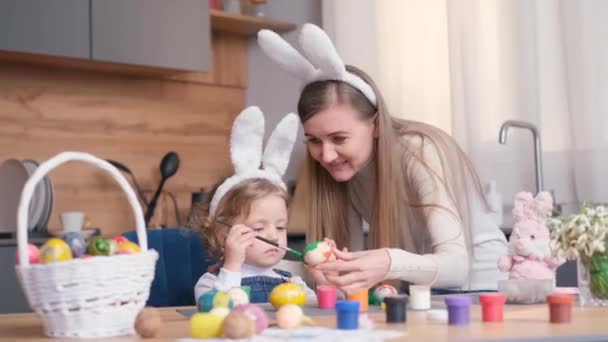 一位漂亮的金发母亲和她的女儿画复活节彩蛋 复活节假期的概念 — 图库视频影像