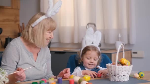 Una Bambina Sua Nonna Dipingono Uova Pasqua Seduti Tavolo Festivo — Video Stock