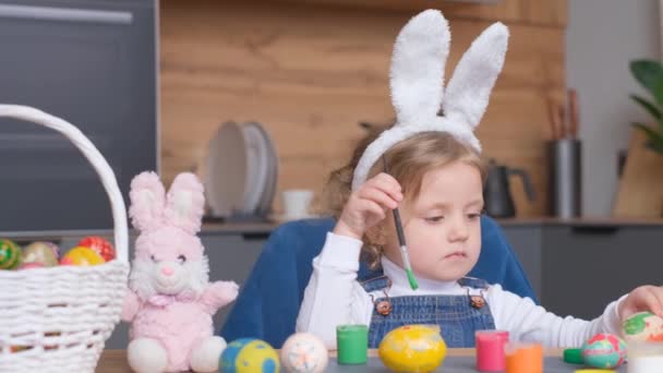 Mała Dziewczynka Wielkanocnymi Uszami Maluje Wielkanocne Jajka Domu Urocze Dziecko — Wideo stockowe