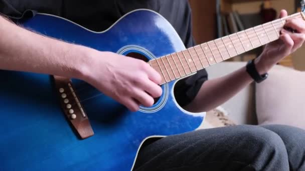 男性ミュージシャンが青いアコースティックギターを演奏する 現代の若いヒップスターギタリストはギターを演奏する おしゃれな巻き毛 — ストック動画