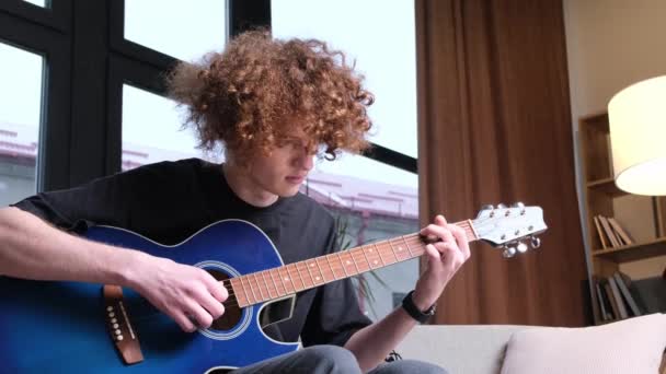 Lockig Rödhårig Pojke Med Amerikanskt Utseende Lär Sig Spela Gitarr — Stockvideo