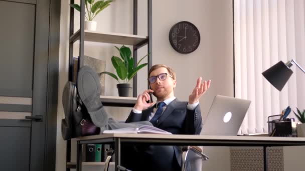 Szczęśliwy Biznesmen Rozmawiający Przez Telefon Pochylający Się Przy Stole Stopami — Wideo stockowe