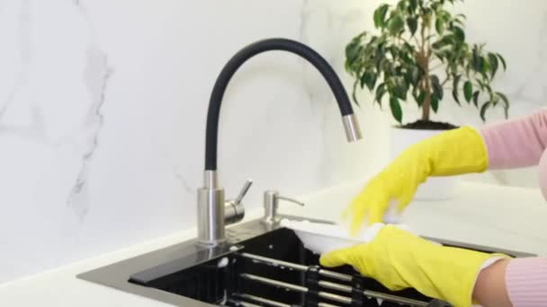 Μια Νοικοκυρά Πλένει Πιάτα Στο Νεροχύτη Της Κουζίνας Χρησιμοποιώντας Απορρυπαντικό — Αρχείο Βίντεο