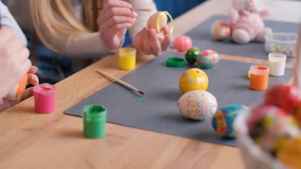 一个快乐的家庭为复活节画彩蛋 他们穿着兔子耳朵的衣服 复活节假期的概念 4K视频 — 图库视频影像