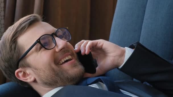 一个快乐的商人在休息的时候通过电话交谈 靠近点商人在办公室沙发上休息 以此作为商业概念 — 图库视频影像
