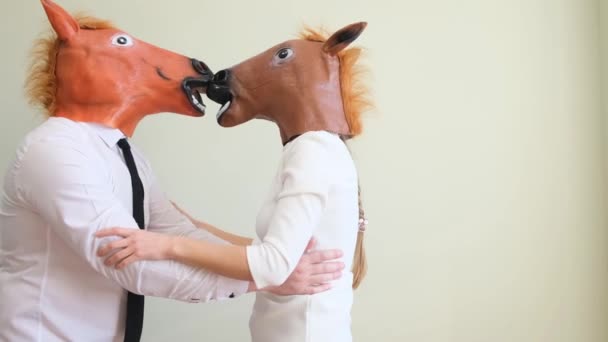 白いシャツと馬のマスクを着た男と女が白い背景に立ってキスをする 楽しいですね ユーモアの概念 — ストック動画