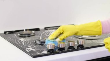 Modern bir mutfak sobasını banyo bezi ve köpükle yıkıyorum. Eldivenli bir kadın metal mutfak sobasını yıkıyor. Yemek pişirmek için elektrikli soba..