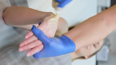 Ellerin deplasmanı. Bir güzellik uzmanının müşterinin elini cilalarken yakın plan fotoğrafı. Tüy dökümü için şeker ezmesi. Şekerleme