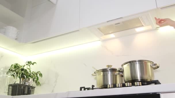 一个女人打开炉子上方的盖子做饭 白色的新现代厨房 — 图库视频影像