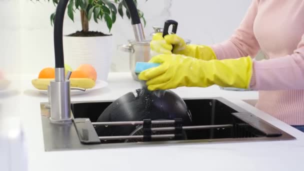 キッチンの清潔感 黄色の手袋の女性は モダンな白いキッチンで鍋を洗っています 清潔感 — ストック動画