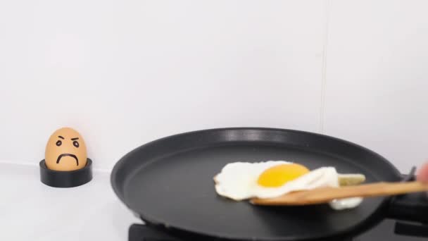 男の手は木の棒でスクランブルエッグを反転させます 白い背景に鍋に卵をフライ — ストック動画