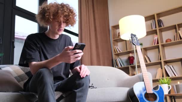 変な髪型の若い男が電話で話している 幸せな巻き毛の若い男が電話で話している 技術及び通信 — ストック動画