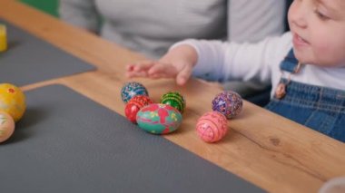 Büyükanne ve torun Paskalya için yumurta boyuyor, tavşan kulağı takıyorlar. Paskalya tatili konsepti. 4k video