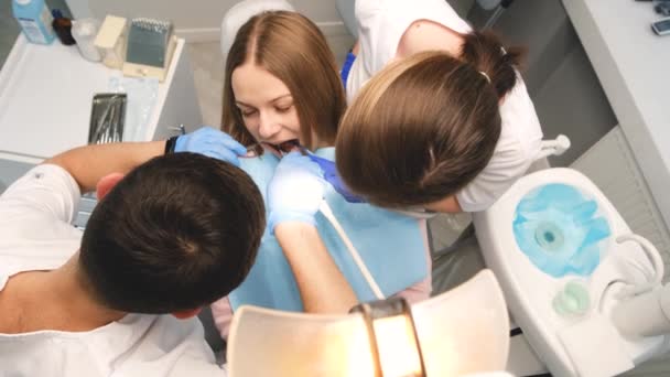 Diş Kliniğinde Koruyucu Maskeli Iki Doktor Bir Kadın Hastaya Hizmet — Stok video